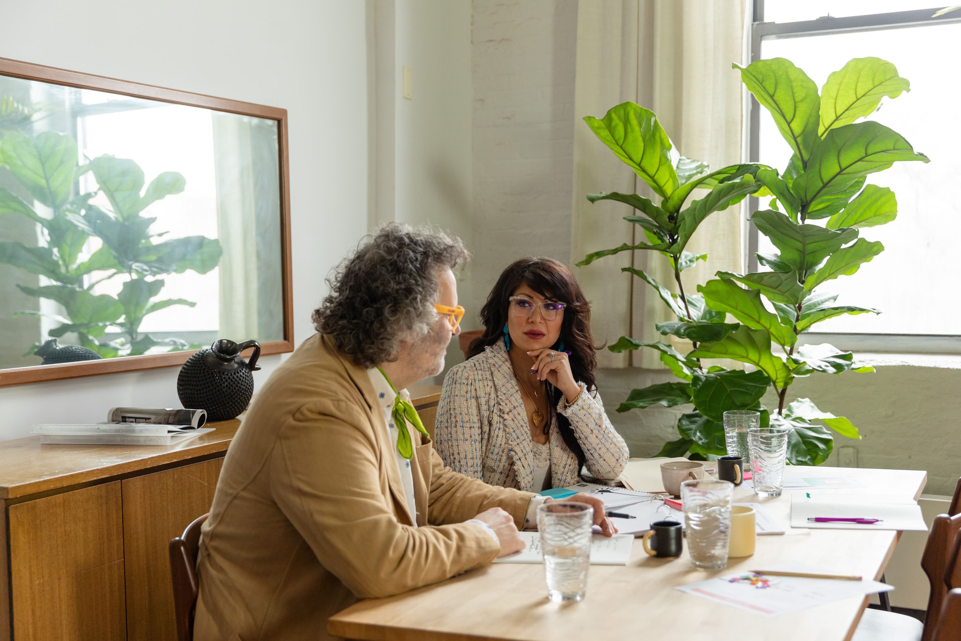 Two professionals discussing documents at a light-filled table.